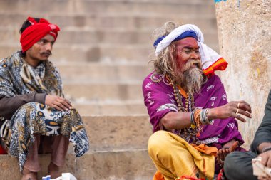 Varanasi, Uttar Pradesh, Hindistan - 20 Ocak 2024: Varanasi 'deki çetelerin yakınındaki ghatlarda oturan geleneksel bir sadhu baba resmi. Sadhu, Kaşhi 'de Ganga yakınlarında ayinler düzenler..