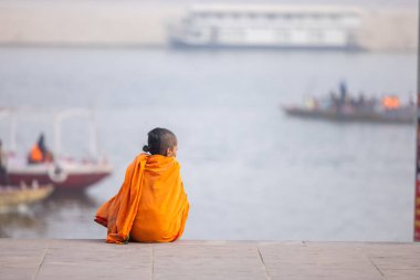 Varanasi, Uttar Pradesh, Hindistan - 20 Ocak 2024: Gurukul 'un ya da okulun kimliği belirsiz erkek öğrencileri kış sabahı Varanasi' de kutsal nehir keneviri yakınlarındaki ghat üzerinde oturuyorlar.