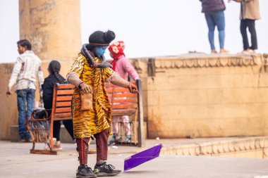 Varanasi, Uttar Pradesh, Hindistan - 20 Ocak 2024: Varanasi 'de kış sabahı Ganga nehrinde boyalı yüzüyle yürüyen Lord Shiv gibi giyinmiş genç bir çocuğun portresi.