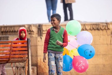 Varanasi, Uttar Pradesh, Hindistan - 20 Ocak 2024: Varanasi 'de kış sabahı Ganga nehrinde boyalı yüzüyle yürüyen Lord Shiv gibi giyinmiş genç bir çocuğun portresi.