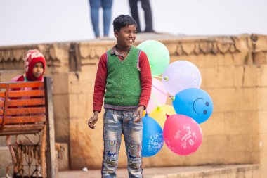 Varanasi, Uttar Pradesh, Hindistan - 20 Ocak 2024: Varanasi 'de kış sabahı Ganga nehrinde boyalı yüzüyle yürüyen Lord Shiv gibi giyinmiş genç bir çocuğun portresi.