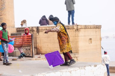 Varanasi, Uttar Pradesh, Hindistan - 20 Ocak 2024: Varanasi 'de kış sabahı Ganga nehrinde boyalı yüzüyle yürüyen Lord Shiv gibi giyinmiş genç bir çocuğun portresi.