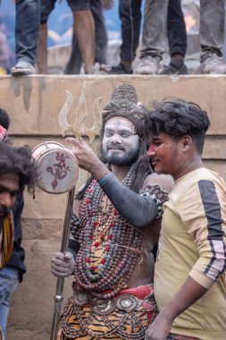 Varanasi, Uttar Pradesh, Hindistan - 20 Mart 2024: Masan Holi, Harishchandra ghat 'ta düzenlenen kutlama sırasında efendi shiva gibi giyinmiş kuru külle boyanmış bir erkek dindar portresi.