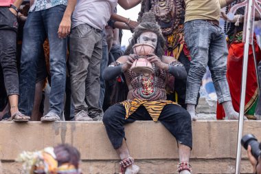 Varanasi, Uttar Pradesh, Hindistan - 20 Mart 2024: Masan Holi, Harishchandra ghat 'ta düzenlenen kutlama sırasında efendi shiva gibi giyinmiş kuru külle boyanmış bir erkek dindar portresi.