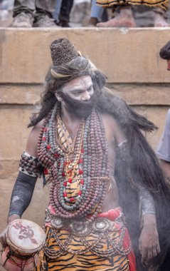 Varanasi, Uttar Pradesh, Hindistan - 20 Mart 2024: Masan Holi, Harishchandra ghat 'ta düzenlenen kutlama sırasında efendi shiva gibi giyinmiş kuru külle boyanmış bir erkek dindar portresi.