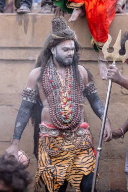 Varanasi, Uttar Pradesh, Hindistan - 20 Mart 2024: Masan Holi, Harishchandra ghat 'ta düzenlenen kutlama sırasında efendi shiva gibi giyinmiş kuru külle boyanmış bir erkek dindar portresi.
