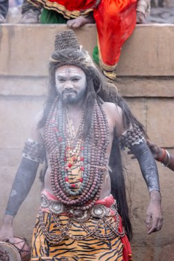 Varanasi, Uttar Pradesh, Hindistan - 20 Mart 2024: Masan Holi, Harishchandra ghat 'ta düzenlenen kutlama sırasında efendi shiva gibi giyinmiş kuru külle boyanmış bir erkek dindar portresi.