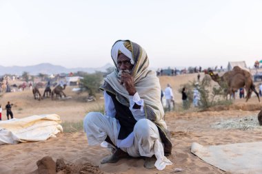 Bikaner, Rajasthan, Hindistan - 15 Ocak 2023: Siluet konsepti, gökyüzünün altındaki tepelerin tepesinde duran develer. Kimliği belirlenemeyen kişi.