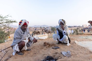 Bikaner, Rajasthan, Hindistan - 15 Ocak 2023: Siluet konsepti, gökyüzünün altındaki tepelerin tepesinde duran develer. Kimliği belirlenemeyen kişi.