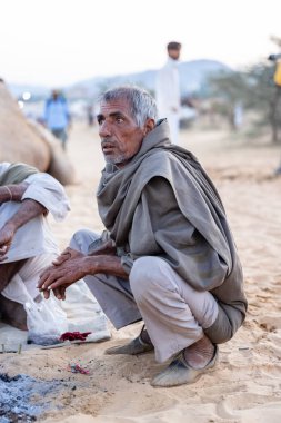 Puşkar, Rajasthan, Hindistan - Kasım 09 2024: Geleneksel giysili rajasthani erkek portresi çöl panayırında deve fuarı sırasında deve ticareti sırasında sarıklı.