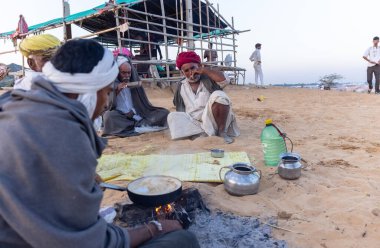 Puşkar, Rajasthan, Hindistan - Kasım 09 2024: Geleneksel beyaz giysili rajasthani erkek portresi çöl panayırında deve fuarı sırasında deve ticareti sırasında sarıklı.