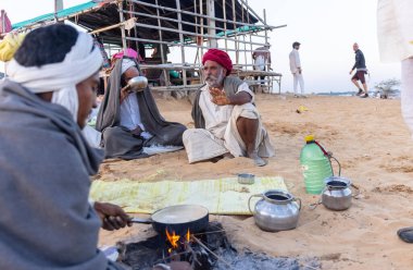 Puşkar, Rajasthan, Hindistan - Kasım 09 2024: Geleneksel beyaz giysili rajasthani erkek portresi çöl panayırında deve fuarı sırasında deve ticareti sırasında sarıklı.