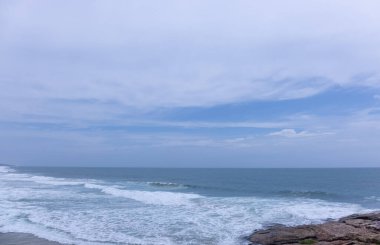 Plaj manzarası, deniz dalgaları ve hindistan cevizi ağaçlarıyla güzel bir kumsal manzarası. Doğa manzarası. 