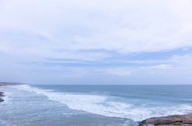 Plaj manzarası, deniz dalgaları ve hindistan cevizi ağaçlarıyla güzel bir kumsal manzarası. Doğa manzarası. 