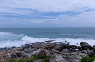 Plaj manzarası, deniz dalgaları ve hindistan cevizi ağaçlarıyla güzel bir kumsal manzarası. Doğa manzarası. 