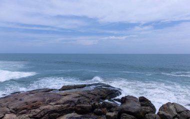 Plaj manzarası, deniz dalgaları ve hindistan cevizi ağaçlarıyla güzel bir kumsal manzarası. Doğa manzarası. 