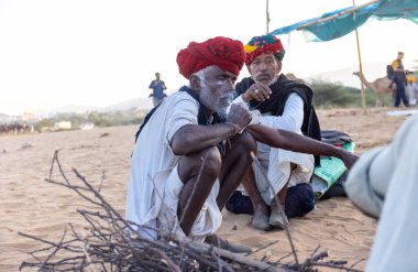 Puşkar, Rajasthan, Hindistan - Kasım 09 2024: Geleneksel giysili rajasthani erkek portresi çöl panayırında deve fuarı sırasında deve ticareti sırasında sarıklı.