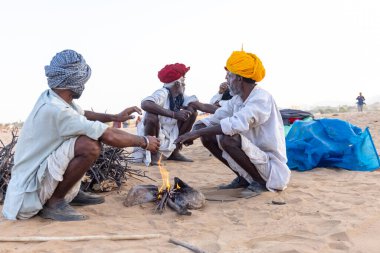 Puşkar, Rajasthan, Hindistan - Kasım 09 2024: Geleneksel beyaz giysili rajasthani erkek portresi çöl panayırında deve fuarı sırasında deve ticareti sırasında sarıklı.
