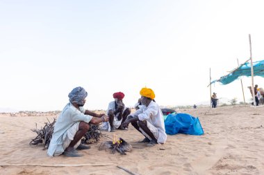Puşkar, Rajasthan, Hindistan - Kasım 09 2024: Geleneksel giysili rajasthani erkek portresi çöl panayırında deve fuarı sırasında deve ticareti sırasında sarıklı.