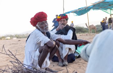 Puşkar, Rajasthan, Hindistan - Kasım 09 2024: Geleneksel giysili rajasthani erkek portresi çöl panayırında deve fuarı sırasında deve ticareti sırasında sarıklı.
