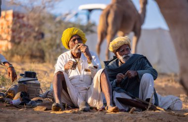 Puşkar, Rajasthan, Hindistan - Kasım 09 2024: Geleneksel giysili bir rajasthani erkek portresi çöl panayırında develerin ticareti sırasında türbanlı..