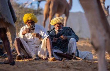 Puşkar, Rajasthan, Hindistan - Kasım 09 2024: Geleneksel giysili bir rajasthani erkek portresi çöl panayırında develerin ticareti sırasında türbanlı..