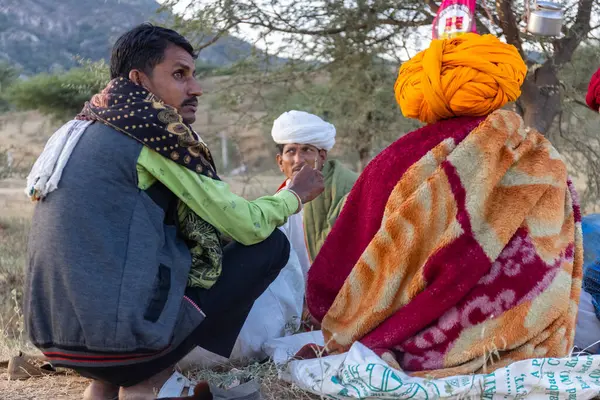 Puşkar, Rajasthan, Hindistan - Kasım 09 2024: Geleneksel beyaz giysili rajasthani erkek portresi çöl panayırında deve fuarı sırasında deve ticareti sırasında sarıklı.