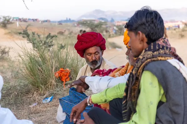 Puşkar, Rajasthan, Hindistan - Kasım 09 2024: Geleneksel beyaz giysili rajasthani erkek portresi çöl panayırında deve fuarı sırasında deve ticareti sırasında sarıklı.