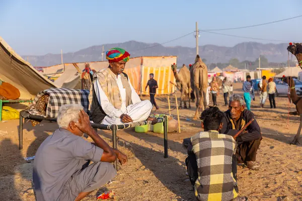 Puşkar, Rajasthan, Hindistan - Kasım 09 2024: Geleneksel giysili bir rajasthani erkek portresi çöl panayırında develerin ticareti sırasında türbanlı..