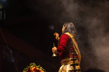 Varanasi, Uttar Pradesh, Hindistan - 20 Ocak 2024: Ganga aarti, Dashashwamedh ghat geleneksel elbise ve Hindu ayinleri ile kutsal nehir keneviri akşam ayini yapan genç bir rahibin portresi.