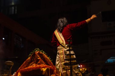 Varanasi, Uttar Pradesh, Hindistan - 20 Ocak 2024: Ganga aarti, Dashashwamedh ghat geleneksel elbise ve Hindu ayinleri ile kutsal nehir keneviri akşam ayini yapan genç bir rahibin portresi.