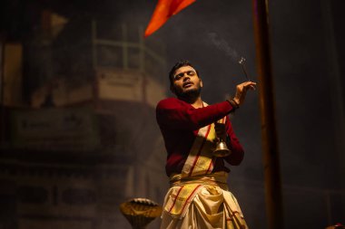 Varanasi, Uttar Pradesh, Hindistan - 20 Ocak 2024: Ganga aarti, Dashashwamedh ghat geleneksel elbise ve Hindu ayinleri ile kutsal nehir keneviri akşam ayini yapan genç bir rahibin portresi.