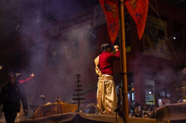 Varanasi, Uttar Pradesh, Hindistan - 20 Ocak 2024: Ganga aarti, Dashashwamedh ghat geleneksel elbise ve Hindu ayinleri ile kutsal nehir keneviri akşam ayini yapan genç bir rahibin portresi.