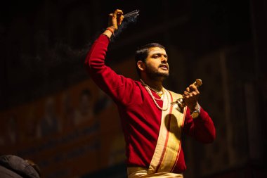 Varanasi, Uttar Pradesh, Hindistan - 20 Ocak 2024: Ganga aarti, Dashashwamedh ghat geleneksel elbise ve Hindu ayinleri ile kutsal nehir keneviri akşam ayini yapan genç bir rahibin portresi.