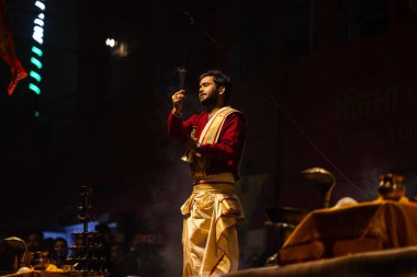 Varanasi, Uttar Pradesh, India - January 20 2024: Ganga aarti, Portrait of a young male priest performing holy river ganga evening aarti at dashashwamedh ghat in traditional dress with hindu rituals.
