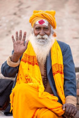 Varanasi, Uttar Pradesh, Hindistan - 20 Ocak 2024: Varanasi 'deki çetelerin yakınındaki ghatlarda oturan geleneksel bir sadhu baba resmi. Sadhu, Kaşhi 'de Ganga yakınlarında ayinler düzenler..