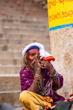 Varanasi, Uttar Pradesh, Hindistan - 20 Ocak 2024: Varanasi 'deki çetelerin yakınındaki ghatlarda oturan geleneksel bir sadhu baba resmi. Sadhu, Kaşhi 'de Ganga yakınlarında ayinler düzenler..
