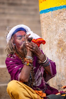 Varanasi, Uttar Pradesh, Hindistan - 20 Ocak 2024: Varanasi 'deki çetelerin yakınındaki ghatlarda oturan geleneksel bir sadhu baba resmi. Sadhu, Kaşhi 'de Ganga yakınlarında ayinler düzenler..