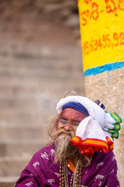 Varanasi, Uttar Pradesh, Hindistan - 20 Ocak 2024: Varanasi 'deki çetelerin yakınındaki ghatlarda oturan geleneksel bir sadhu baba resmi. Sadhu, Kaşhi 'de Ganga yakınlarında ayinler düzenler..