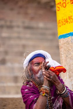 Varanasi, Uttar Pradesh, Hindistan - 20 Ocak 2024: Varanasi 'deki çetelerin yakınındaki ghatlarda oturan geleneksel bir sadhu baba resmi. Sadhu, Kaşhi 'de Ganga yakınlarında ayinler düzenler..