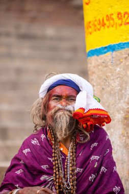 Varanasi, Uttar Pradesh, Hindistan - 20 Ocak 2024: Varanasi 'deki çetelerin yakınındaki ghatlarda oturan geleneksel bir sadhu baba resmi. Sadhu, Kaşhi 'de Ganga yakınlarında ayinler düzenler..