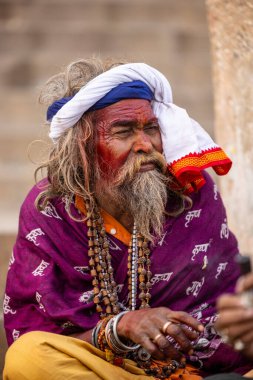 Varanasi, Uttar Pradesh, Hindistan - 20 Ocak 2024: Varanasi 'deki çetelerin yakınındaki ghatlarda oturan geleneksel bir sadhu baba resmi. Sadhu, Kaşhi 'de Ganga yakınlarında ayinler düzenler..