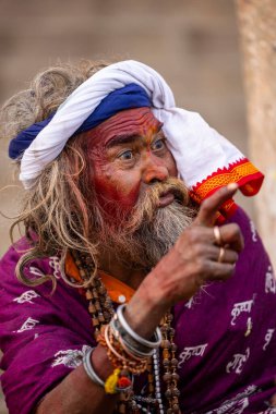 Varanasi, Uttar Pradesh, Hindistan - 20 Ocak 2024: Varanasi 'deki çetelerin yakınındaki ghatlarda oturan geleneksel bir sadhu baba resmi. Sadhu, Kaşhi 'de Ganga yakınlarında ayinler düzenler..