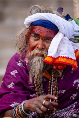 Varanasi, Uttar Pradesh, Hindistan - 20 Ocak 2024: Varanasi 'deki çetelerin yakınındaki ghatlarda oturan geleneksel bir sadhu baba resmi. Sadhu, Kaşhi 'de Ganga yakınlarında ayinler düzenler..