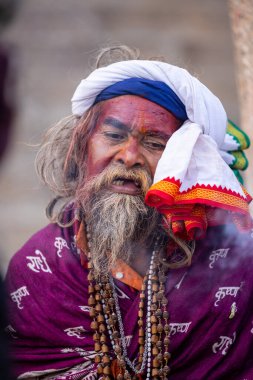 Varanasi, Uttar Pradesh, Hindistan - 20 Ocak 2024: Varanasi 'deki çetelerin yakınındaki ghatlarda oturan geleneksel bir sadhu baba resmi. Sadhu, Kaşhi 'de Ganga yakınlarında ayinler düzenler..