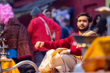 Varanasi, Uttar Pradesh, Hindistan - 20 Ocak 2024: Ganga aarti, Dashashwamedh ghat geleneksel elbise ve Hindu ayinleri ile kutsal nehir keneviri akşam ayini yapan genç bir rahibin portresi.