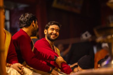 Varanasi, Uttar Pradesh, Hindistan - 20 Ocak 2024: Ganga aarti, Dashashwamedh ghat geleneksel elbise ve Hindu ayinleri ile kutsal nehir keneviri akşam ayini yapan genç bir rahibin portresi.