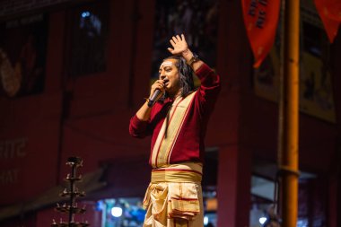 Varanasi, Uttar Pradesh, Hindistan - 20 Ocak 2024: Ganga aarti, Dashashwamedh ghat geleneksel elbise ve Hindu ayinleri ile kutsal nehir keneviri akşam ayini yapan genç bir rahibin portresi.
