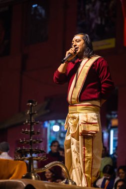 Varanasi, Uttar Pradesh, Hindistan - 20 Ocak 2024: Ganga aarti, Dashashwamedh ghat geleneksel elbise ve Hindu ayinleri ile kutsal nehir keneviri akşam ayini yapan genç bir rahibin portresi.