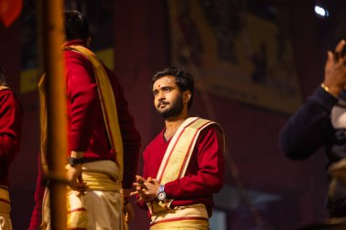 Varanasi, Uttar Pradesh, Hindistan - 20 Ocak 2024: Ganga aarti, Dashashwamedh ghat geleneksel elbise ve Hindu ayinleri ile kutsal nehir keneviri akşam ayini yapan genç bir rahibin portresi.